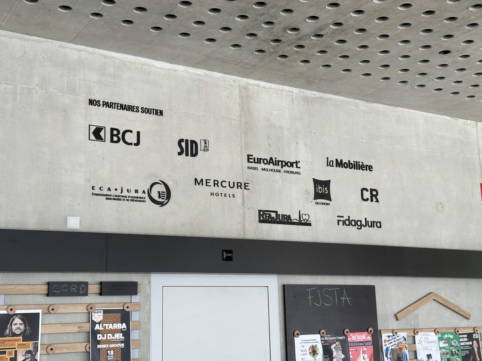 Mur de logos partenaires gravés, hall d'accueil